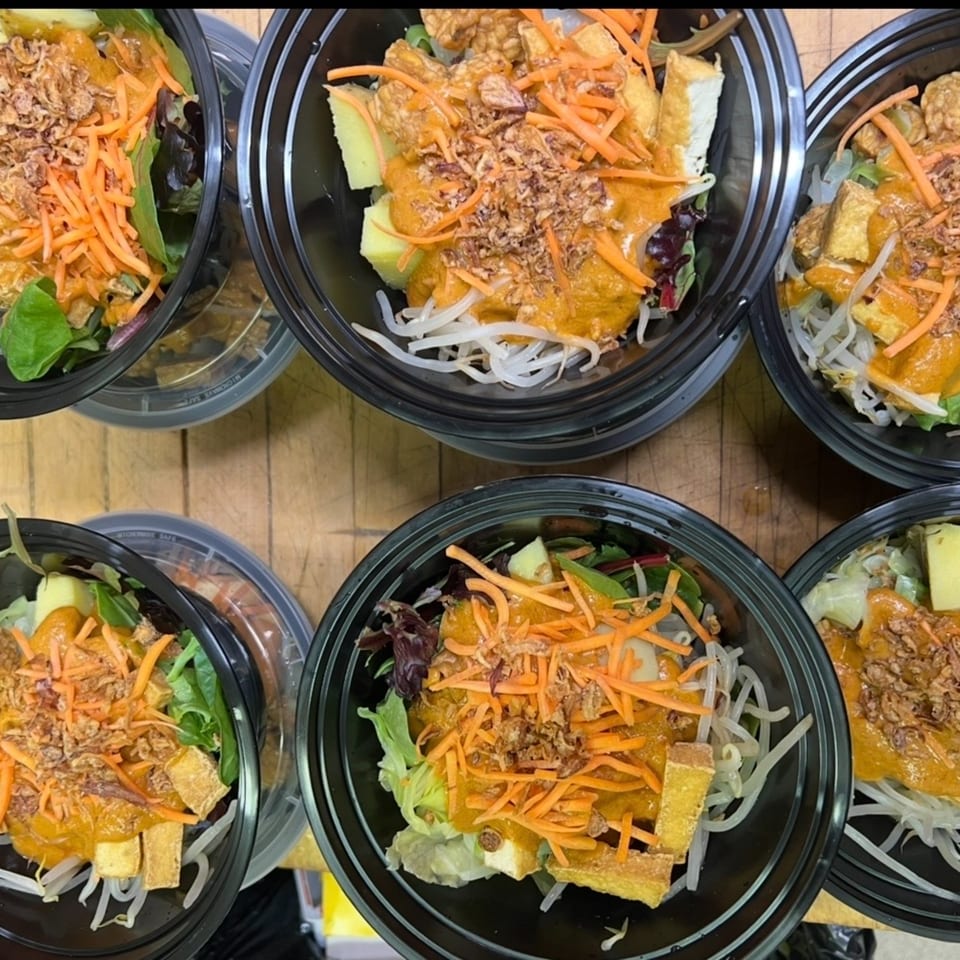 Six Indonesian Gado-Gado salads in black to-go containers, with peanut sauce, tofu, and vegetables.