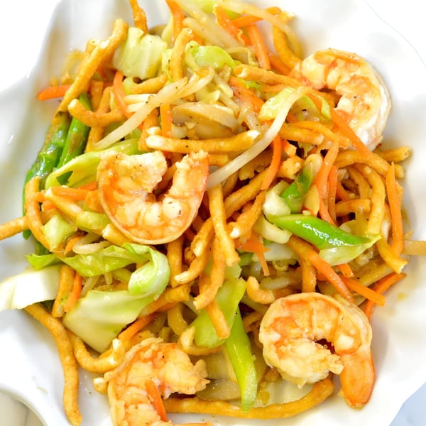Indonesian fried noodles with shrimp, cabbage, carrots, and green beans in a white bowl.